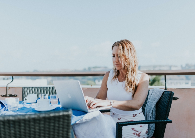 A digital nomad works from a table on a balcony abroad
