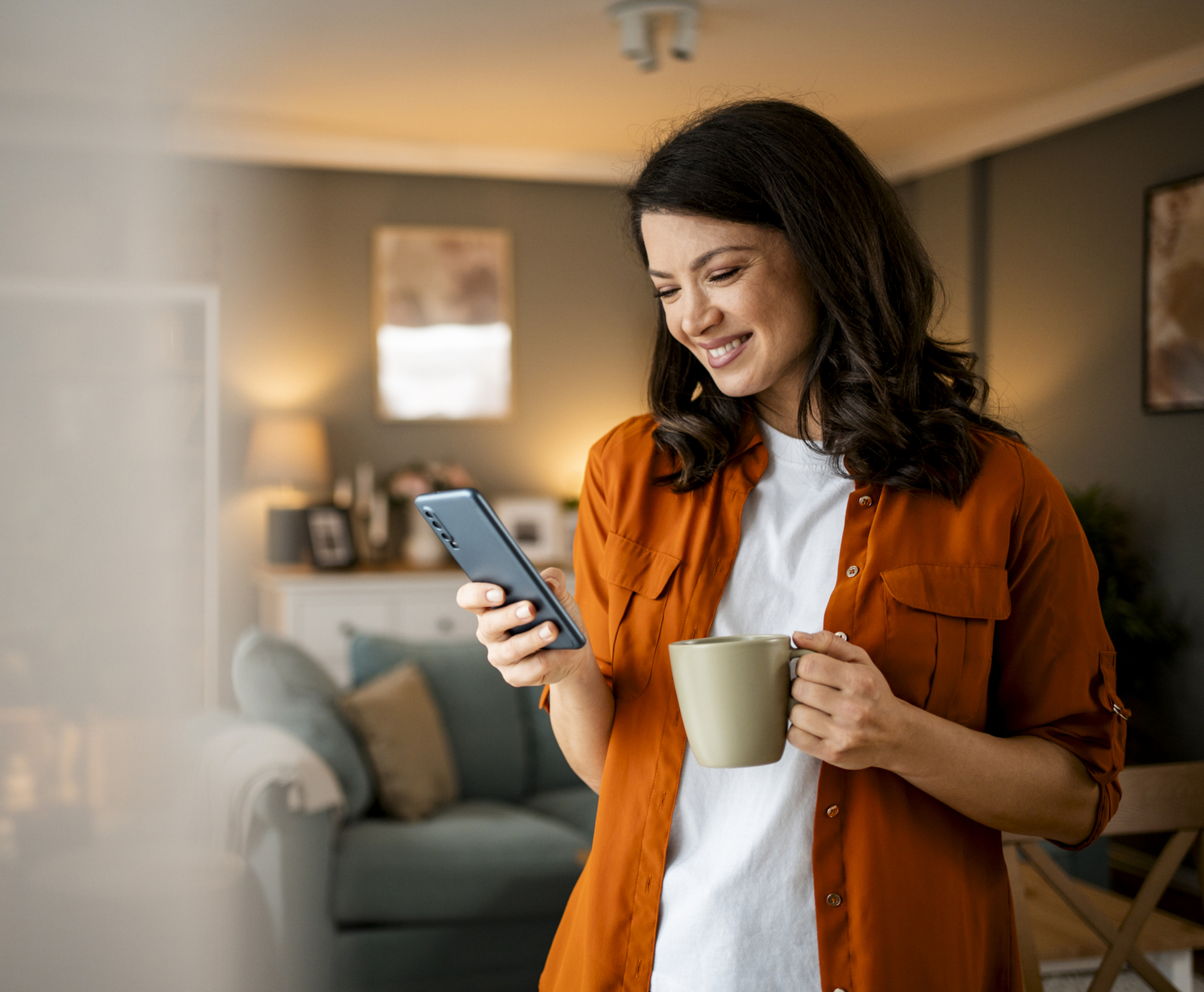 A woman checks her phone whilst enjoying her coffee
