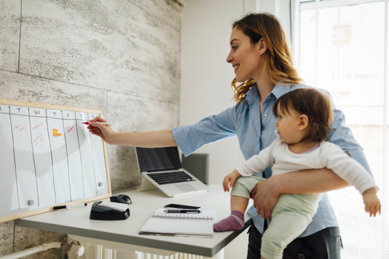 A mother works from home whilst holding her young baby