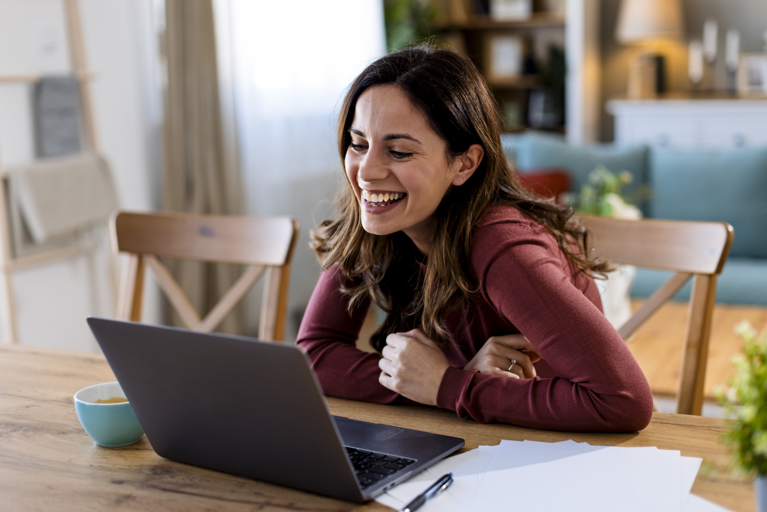 A smiling VA attends a virtual call on her laptop.