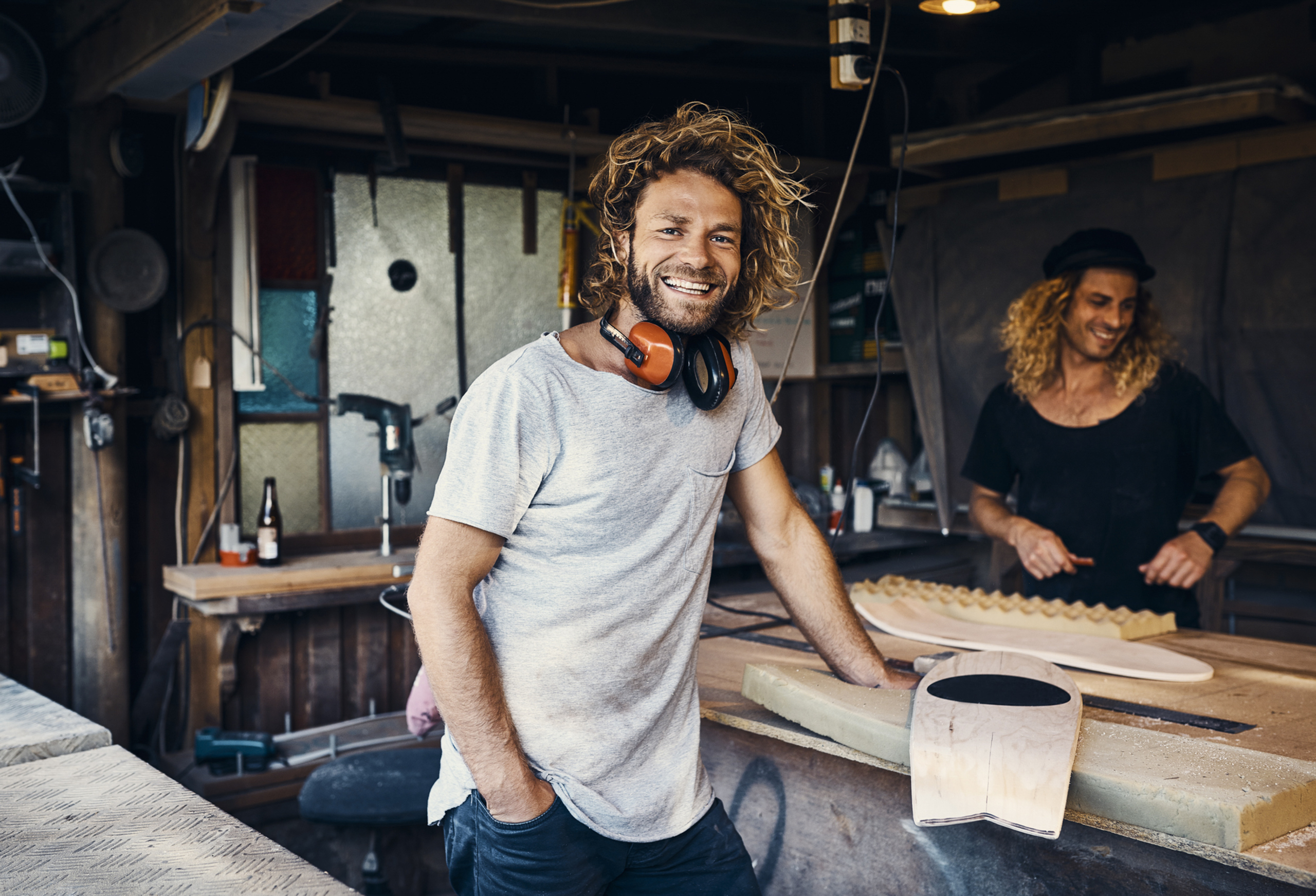 Portrait of two happy men working on skateboards in their workshop