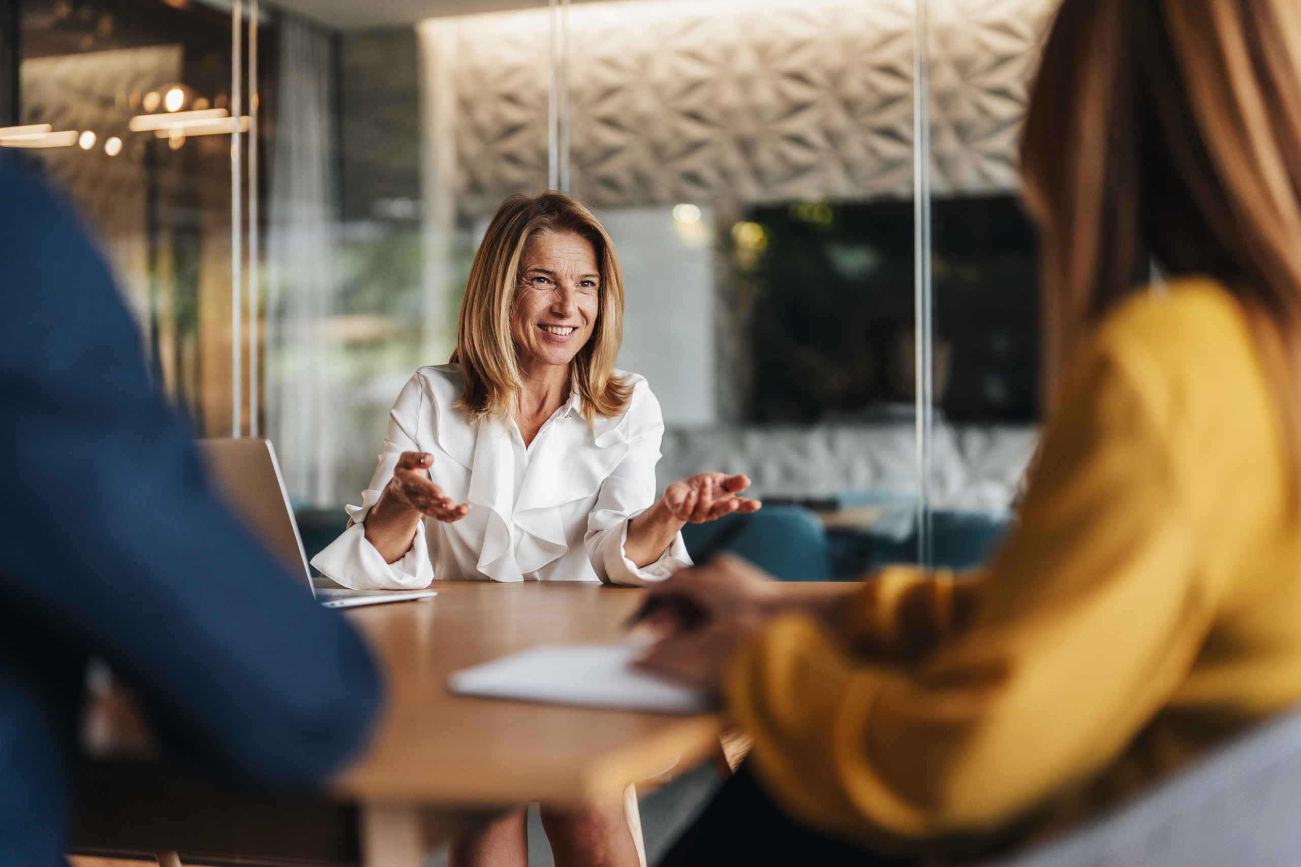 A woman happily talks to two colleagues in a business meeting