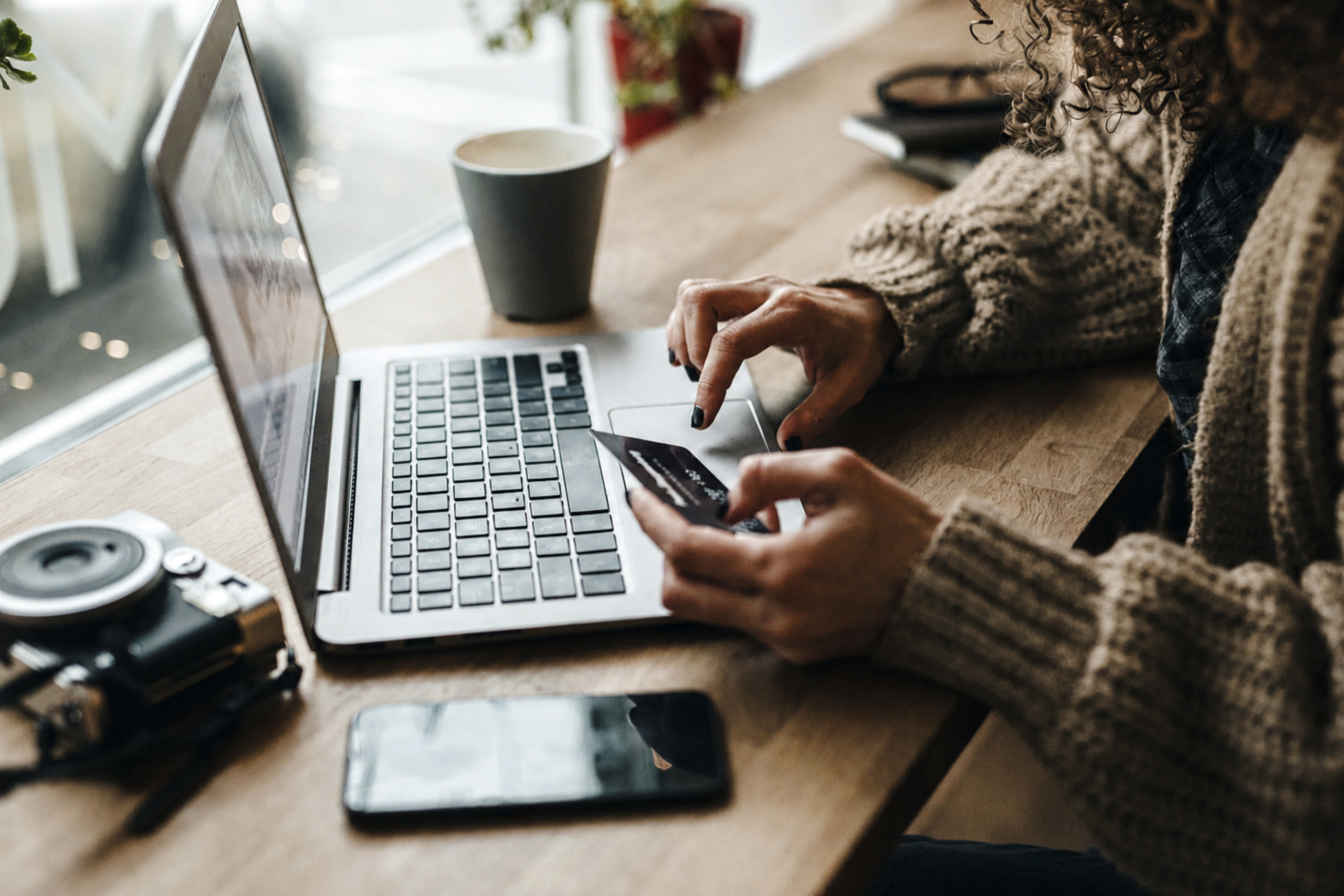 A woman pays for an item she's bought on her laptop with a credit card